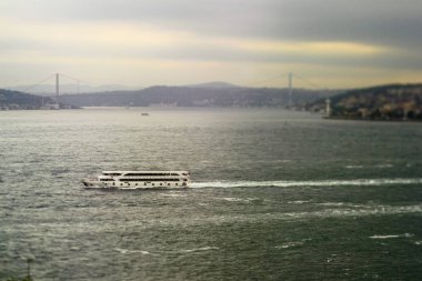 Istanbul 'un Asya ve Avrupa taraflarını bağlayan bir arka planda Bosporus ve Boğaziçi Köprüsünde feribot. Tilt-Shift efekti ile üretilmiştir. Bir teknede seçici odaklama ve bulanık arka plan