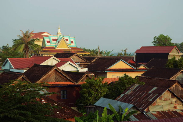 Cityscape of house roofs and wat ( Buddhist temple) on a background. Tropical landscape with palm trees. Stung Treng, Cambodia