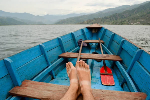 Traveller Pokhara, Nepal Phewa Gölü üzerinde eski ahşap tekne rahatlatıcı. POV görünümü, bacaklar dağ peyzaj arka planda yakın
