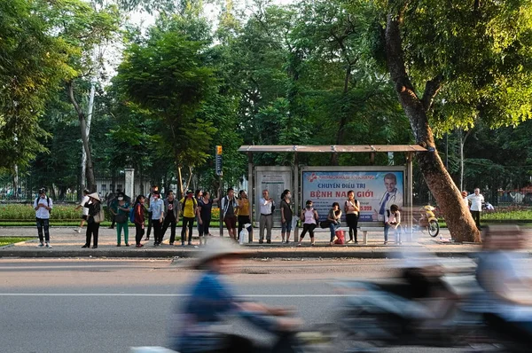 Hanoi, Vietnam - Eylül, 2015: Otobüs durağında insanlar ve yolda motosiklet sürücüleri bulanık.