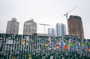 Kiev, Ukrayna - Ocak, 2019: Vinçli yüksek binaların şantiye sinin arka planında çit üzerinde kamu ilan panosu.