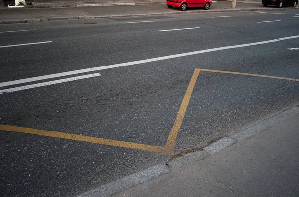 Asfalt üzerinde yol işaretleri ile boş sokak. Kırmızı ve siyah arabalar yürüyüş yollarına park etmiş. Sarı ve beyaz çizgilerle soyut trafik arka planı. Hiçbir durdurma veya park otobüs istasyonu gösteren