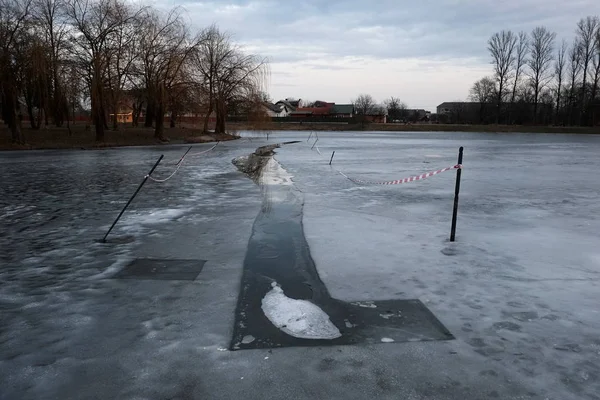 Ice hole in a frozen lake in the city park. Cold winter weather. Kolomyia, Ukraine.