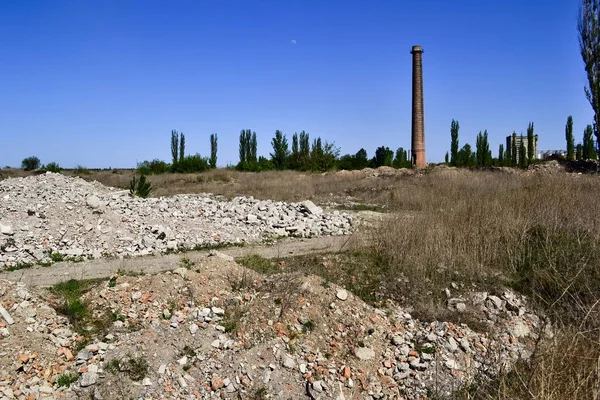 Ruins of an abandoned demolished old plant with high rise chimney. Ruined factory in  Ukraine