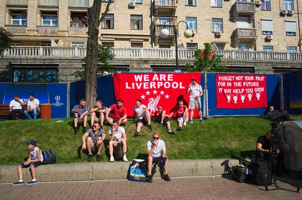 Kiev, Ukrayna - Mayıs 2018: Şampiyonlar Ligi Finali 2018 öncesi Khreshchatyk caddesiüzerinde Kiev şehir merkezinde resmi fan bölgesinde çim üzerinde yatan Liverpool taraftarları. Arkadaki kırmızı posterleri ve bayrakları destekleyin. 
