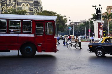 Mumbai, Maharashtra, Hindistan - Aralık, 2016: Kavşakta araba ve otobüs sürerken yayaüzerinde karton kutular taşıyan adam. Mahatma Gandhi yol Kilisesi kapısı kesiştiği bombay şehir trafiği