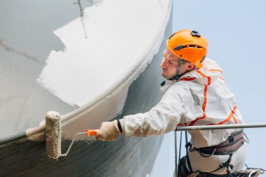 Endüstriyel dağcı kask ve Tekdüzen resim su kulesi. Profesyonel ressam yükseklik üzerinde çalışıyor. Riskli iş. Aşırı işgal.