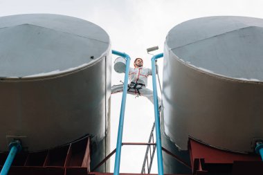 Endüstriyel dağcı kask ve Tekdüzen resim su kulesi. Profesyonel ressam yükseklik üzerinde çalışıyor. Riskli iş. Aşırı işgal.