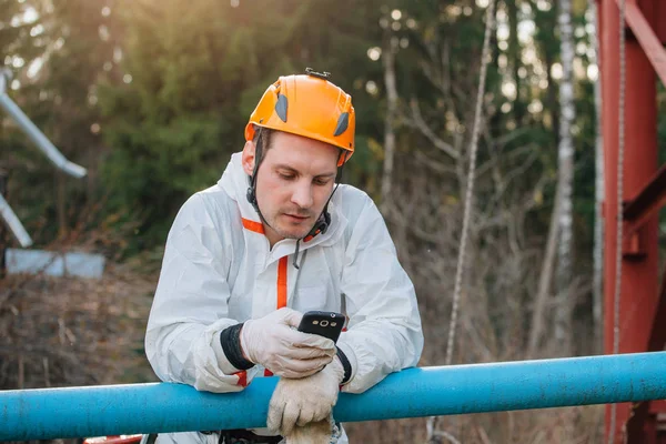 Industrial climber texting someone with his smartphone. Professional workman using phone