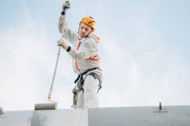 Endüstriyel dağcı kask ve Tekdüzen resim su kulesi. Profesyonel ressam yükseklik üzerinde çalışıyor. Riskli iş. Aşırı işgal.