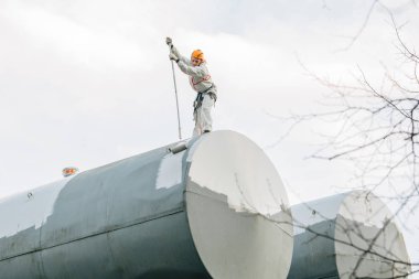 Endüstriyel dağcı kask ve Tekdüzen resim su kulesi. Profesyonel ressam yükseklik üzerinde çalışıyor. Riskli iş. Aşırı işgal.
