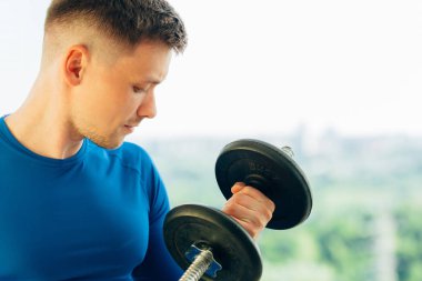 Genç oldukça atletik erkek eğitim pazı dumbbell ile kapatın. Sağlıklı yaşam konsepti.