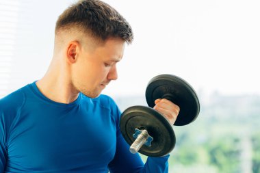 Genç oldukça atletik erkek eğitim pazı dumbbell ile kapatın. Sağlıklı yaşam konsepti.