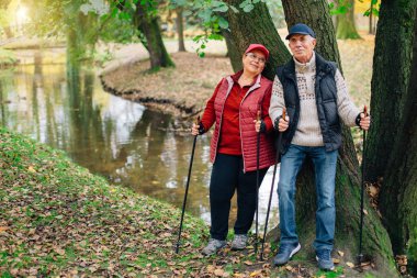 Nordic Polonyalılar renkli sonbahar Park'ta yürüyordunuz oldukça kıdemli çift dururken. Olgun kadın ve yaşlı adam açık havada dinlenme.