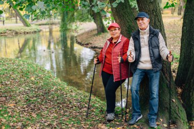 Nordic Polonyalılar renkli sonbahar Park'ta yürüyordunuz oldukça kıdemli çift dururken. Olgun kadın ve yaşlı adam açık havada dinlenme.