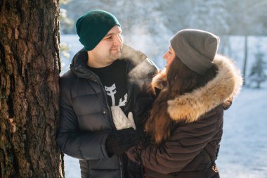 Genç çift aşık kış ormanda eğleniyor. Erkek ve kadın kazaklı bir kar tanesi ile