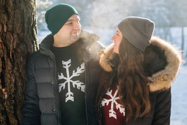 Genç çift aşık kış ormanda eğleniyor. Erkek ve kadın kazaklı bir kar tanesi ile