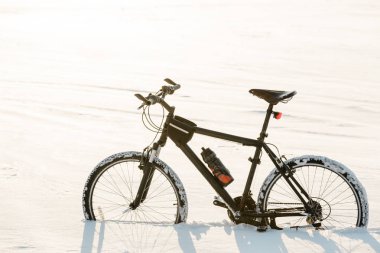 Kış sezonu Bisiklete binme. Şehir merkezinde kar üzerinde siyah bisiklet. Spor yıl kavramının herhangi bir zamanda.