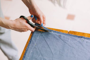 Kapatın. Terzi, terzi tebeşiri ile yaptığı elbisenin kalıbını işaretlediği bir rulo kumaşı kesiyor..