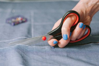 Kapatın. Terzi, terzi tebeşiri ile yaptığı elbisenin kalıbını işaretlediği bir rulo kumaşı kesiyor..