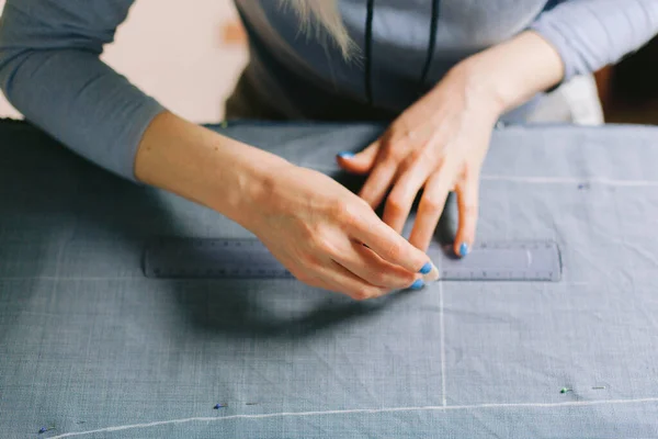 Close up. Tailor marking out the pattern of the garment she is making with tailors chalk. Working at home