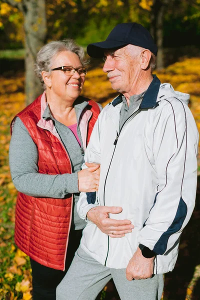 Happy senior couple in love in autumn park. Smiling mature man and old woman having fun outdoors