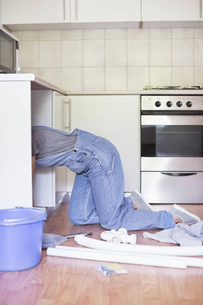台所の流しの下で働く熟練した女性 — ストック写真