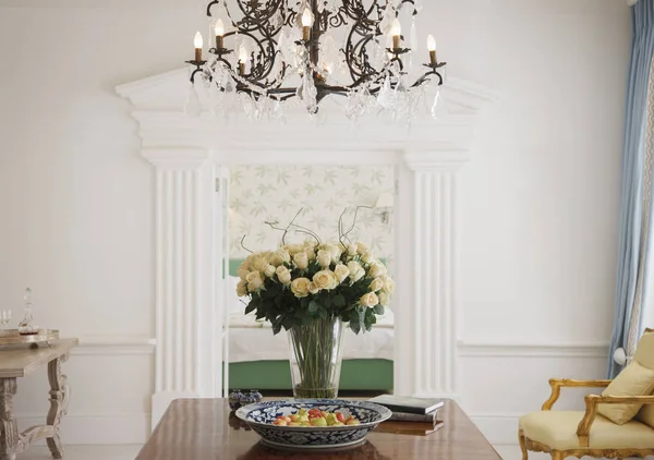 Lustre au-dessus bouquet de rose sur la table dans le foyer de luxe — Photo de stock