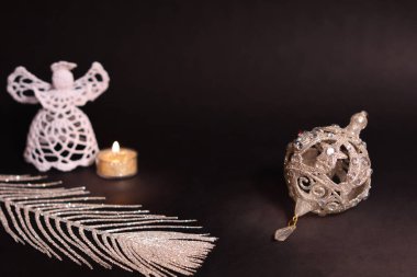 Noel süslemeleri siyah arka plan üzerine. Beyaz melek, mum, gümüş tüy ve Noel ağacı biblo