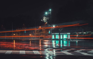 Sokak gece lambaları, arabaların farları açık.