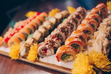 Büyük bir Suşi Rolls-Ilık Ebi Sake Unagi Baharı. Geleneksel restoranda bir tabakta Japon çiğ balığından bir sürü Philadelphia dürümü var. Japon yemek menüsü servisi