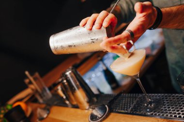 Barmen, barın tezgahına süzgeç gibi beyaz kokteyl döker. Profesyonel bakış açısı. Moda tarzı alkollü içecek. Gece kulübünde tasarımcılar ve konsept servisi barmeni.