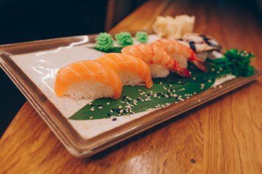 Büyük bir Suşi Rolls-Ilık Ebi Sake Unagi Baharı. Geleneksel restoranda bir tabakta Japon çiğ balığından bir sürü Philadelphia dürümü var. Japon yemek menüsü servisi