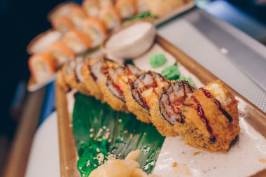 Büyük bir Suşi Rolls-Ilık Ebi Sake Unagi Baharı. Geleneksel restoranda bir tabakta Japon çiğ balığından bir sürü Philadelphia dürümü var. Japon yemek menüsü servisi