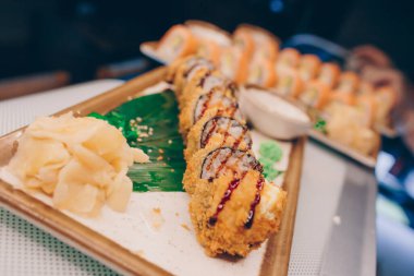 Büyük bir Suşi Rolls-Ilık Ebi Sake Unagi Baharı. Geleneksel restoranda bir tabakta Japon çiğ balığından bir sürü Philadelphia dürümü var. Japon yemek menüsü servisi