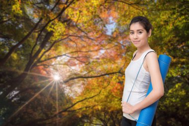Onun yoga mat doğa park açık tutan Genç Asyalı kadın. Yoga ve meditasyon sağlık için iyi faydaları vardır.