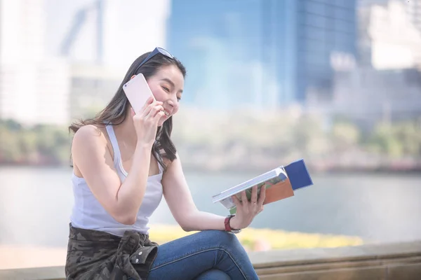 Hermosa mujer turista asiática leyendo el libro guía de viaje en busca de turistas punto de interés. Viajes de vacaciones en verano . — Foto de Stock