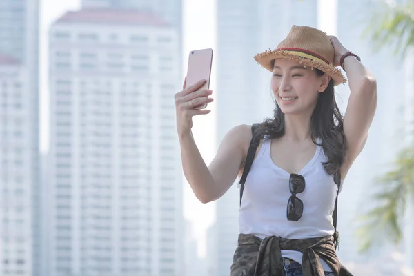 Hermosa mujer turista asiática tomando selfies en un teléfono inteligente en el centro urbano de la ciudad. Viajes de vacaciones en verano . — Foto de Stock