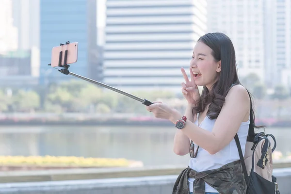 美丽的亚洲旅游妇女采取在城市市中心的智能手机自拍。夏季度假旅行. — 图库照片