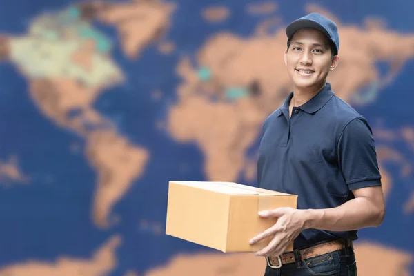 전자 상거래 및 물류 개념에 대한 배경에 글로벌지도가있는 골판지 상자를 들고있는 아시아 배달원. — 스톡 사진