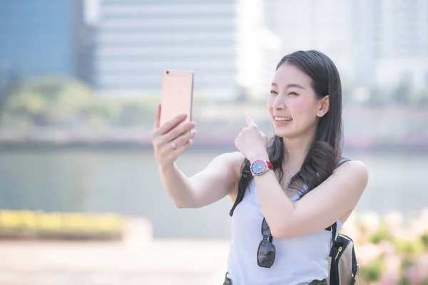 Piękny Asian kobieta cieszyć się przy pomocy wideo rozmowa technologia u pewien smartphone w miejski miasto Śródmieście. — Zdjęcie stockowe