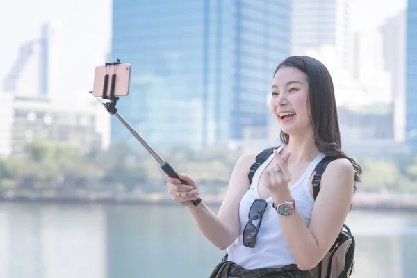 Hermosa mujer asiática disfrutar el uso de la tecnología de videollamadas en un teléfono inteligente en el centro urbano — Foto de Stock