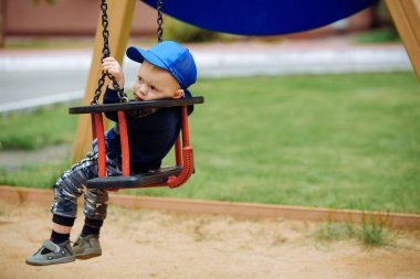 Üzgün çocuk salıncakta oturur ve yüzünü çevirir.