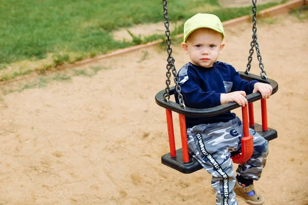 A criança está montando em um balanço, um playground, 1-2 ano velho — Fotografia de Stock