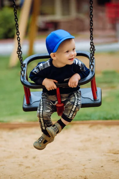 Bonito menino 1-2 anos, sentado em um balanço, playground, close — Fotografia de Stock