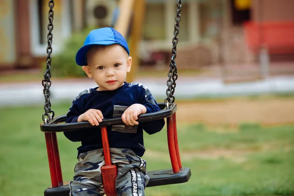 Bonito menino 1-2 anos, sentado em um balanço, playground, close — Fotografia de Stock