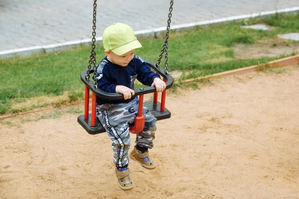 A criança está montando em um balanço, um playground, 1-2 ano velho — Fotografia de Stock