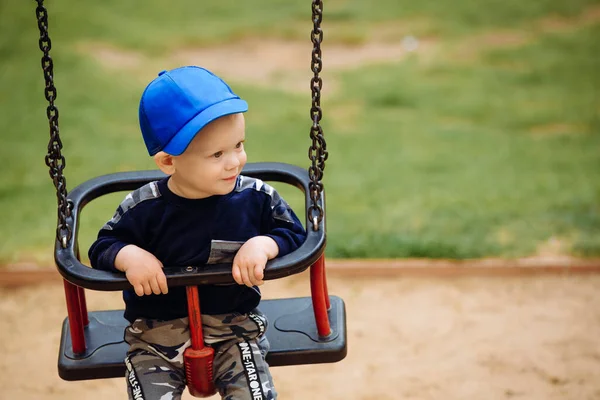 1-2 anos de idade menino sentado em um balanço, playground, close-up — Fotografia de Stock