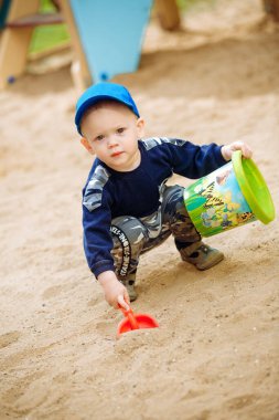 Bir çocuk kumda bir çukur kazıyor.