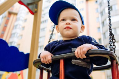 Komik ve yakışıklı çocuk sevinir, salıncakta sallanır, parkta oynar.